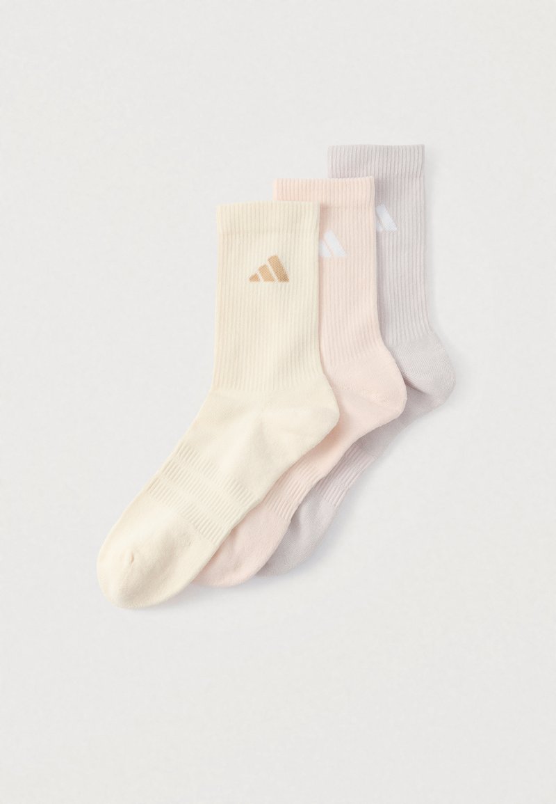 Trois paires de chaussettes côtelées : crème, rose clair et gris clair. Chacune présente un petit logo de couleur contrastante. Texture de tissu douce.