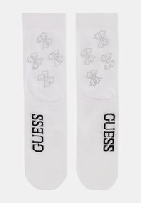 Hvide sokker med sølv rhinesten-logoer og sort "GUESS" tekst. Fremstillet af blødt materiale med en glat tekstur og almindelig form.