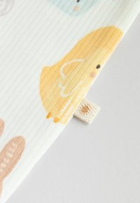 Mjukt bomullstyg med ett urval av färgglada djurmönster, inklusive en gul kyckling, med en texturerad ribbad design och sidotagg.