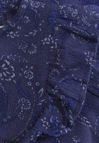 Marineblauer Stoff mit floralem Muster, der über Rüschensäume und eine weiche Textur verfügt. Das Design weist komplexe Details und eine glatte Oberfläche auf.
