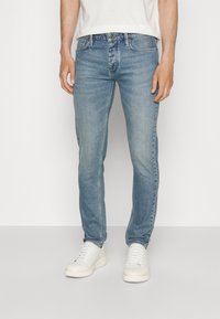 Ljusblå denimjeans med en slim fit, med subtila blekningar, fem fickor och knappgylf. Bärs med vita sneakers.