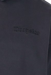 Mørkegrå sweatshirt med et tekstureret, prægede logo med teksten "Dropsize" foran. Lavet af blødt, glat materiale.