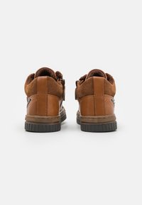 Chaussures en cuir et en daim marron avec une finition texturée, un col rembourré et une semelle en caoutchouc. Le design présente des accents cousus et un style bas.