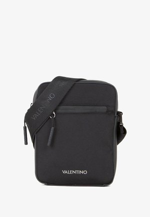 Sac bandoulière en nylon noir de forme rectangulaire, finition mate, compartiment zippé, logo embossé sur le devant, avec une bandoulière détachable.