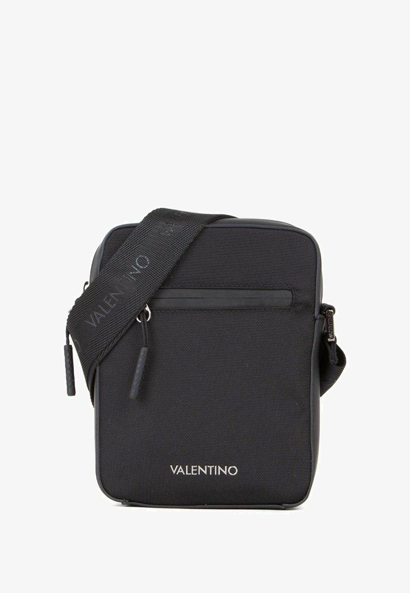 Sac bandoulière en nylon noir de forme rectangulaire, finition mate, compartiment zippé, logo embossé sur le devant, avec une bandoulière détachable.