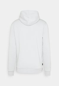 Sweat à capuche blanc uni vu de dos avec manches longues et poignets côtelés sur un fond gris.