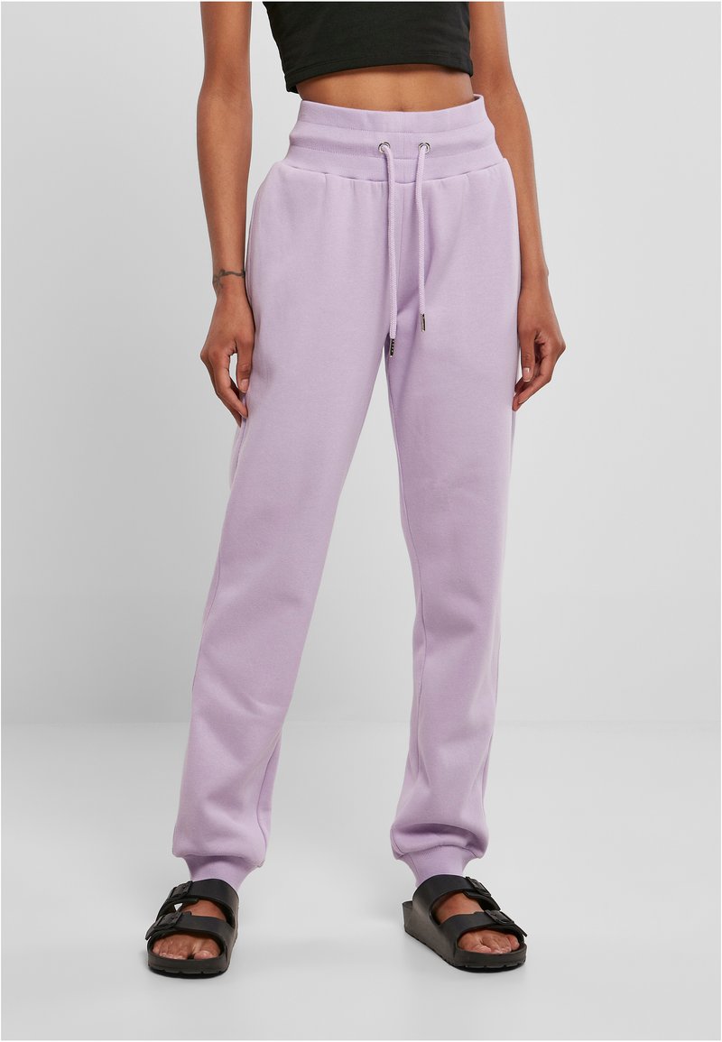 Pantalons de survêtement lilas avec une taille haute, fermeture à cordon de serrage et poignets côtelés, associés à des sandales noires à enfiler.