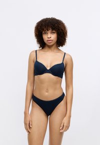 Granatowy bezprzewodowy stanik i pasujące majtki w bikini. Gładki materiał, regulowane ramiączka oraz szczegóły z logo na pasku majtek.