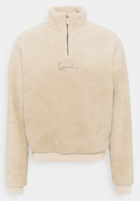 Pullover in pile beige con colletto alto, mezzo zip e logo ricamato. Texture morbida e polsini elastici. Forma casual e boxy.