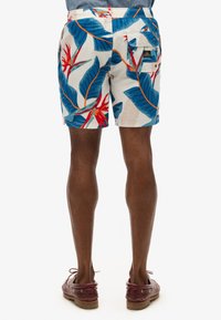 Bañadores para hombre con un vibrante diseño tropical que presenta hojas azules y flores rojas. Fabricados con un material ligero y con una cintura elástica.