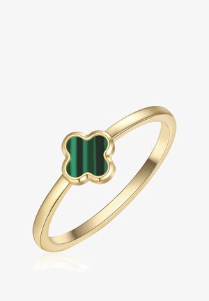 Anillo de banda de oro con una piedra verde en forma de trébol de cuatro hojas, engastada en un bisel liso, fotografiado sobre un fondo blanco.