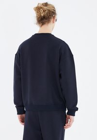 Dunkelblaues Sweatshirt mit einem lockeren Schnitt, gerippten Bündchen und Saum sowie einer glatten Textur. Mit Rundhalsausschnitt und überschnittenen Schultern.