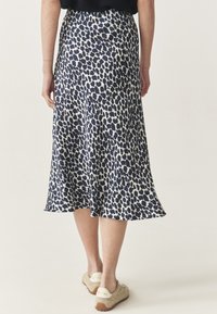 Kesedua panjang, rok melebar dengan cetakan leopard abstrak navy dan putih, terbuat dari kain ringan dengan tekstur yang halus.