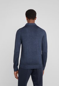 Dunkelblaues Langarm-Pullover mit Kragen, aus strukturiertem Strickmaterial. Mit gerippten Bündchen und Saum, das eine taillierte Silhouette präsentiert.