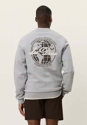 Sudadera gris con un diseño gráfico redondo que incluye un globo terráqueo, el texto "Les Deux" y "International Sporting Goods Established in 2011."