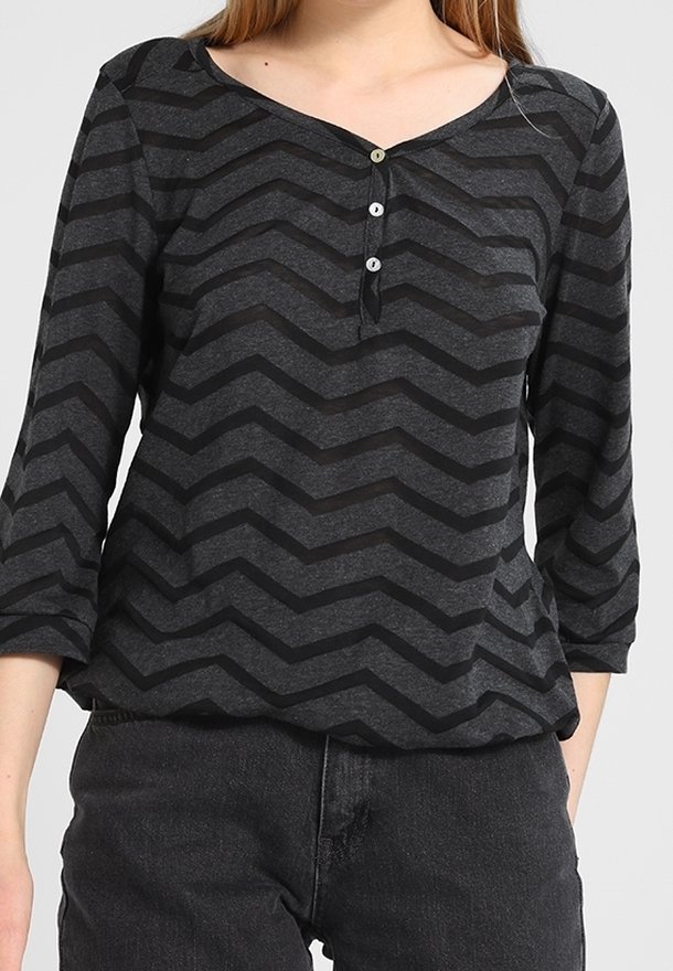 Grå långärmad topp med ett svart chevronmönster, med en V-ringning och tre knappar framtill. Mjuk tyg med avslappnad passform.