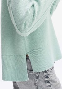 Mintgrüner Strickpullover mit geripptem Saum, seitlichem Schlitzdetail und strukturierten Ärmeln. Hergestellt aus weichem, leichtem Stoff.