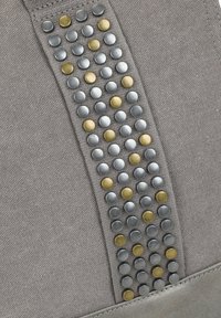 Grijze stoffen tas met een gespikkeld ontwerp, featuring afwisselend zilveren en gouden studs die in verticale rijen langs het midden zijn gerangschikt.