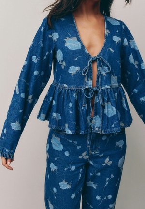 Zestaw z kurtką i spodniami z dżinsu w jasnoniebieski kwiatowy wzór, kurtka z głębokim dekoltem w kształcie litery V, dwoma wiązaniami z przodu oraz dolnym brzegiem z baskinką.