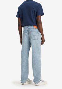 Ljusblå denimjeans med en avslappnad passform, med en klassisk femficksdesign och en brun läderlogotyp på baksidan.