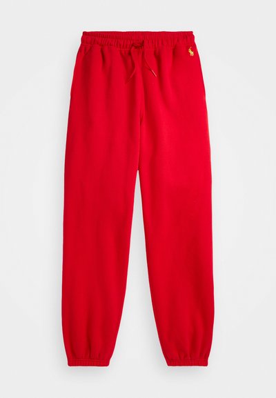 Rote Jogginghose mit elastischem Bund und Kordelzug. Elastische Bündchen an den Knöcheln. Mit einem kleinen Logo auf der oberen linken Seite.