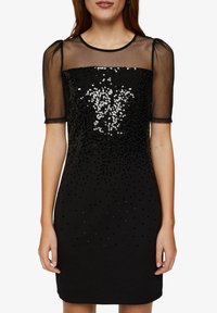 Černé šaty se třpytkami s krátkými průsvitnými balónovými rukávy, zaobleným výstřihem a přiléhavým siluetou. Vyznačují se gradientem třpytek pro texturu.