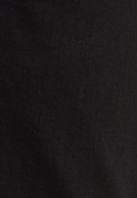 Gros plan sur la texture d’un tissu noir avec un motif de tissage visible et de subtiles particules de peluches.