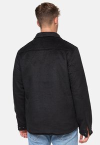 Czarna polarowa kurtka z kołnierzem, widocznymi szwami i mankietami na zatrzaski. Miękka w dotyku o prostym kroju.