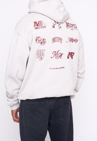 Grijze hoodie van katoen met verschillende bedrukte logo's in donkerrood, voorzien van een capuchon met trekkoord en geribde manchetten. Zwarte broek met zakken.