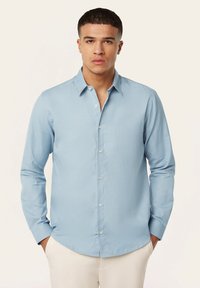 Lichtblauwe lange mouwen shirt van een gladde stof, met een knoopsluiting aan de voorkant, een puntige kraag en een subtiele verticale textuur.