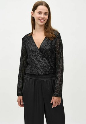 Crni wrap top s dugim rukavima, s teksturom od šljokica i dubokim dekolteom. Kombinira se s crnim širokim hlačama.