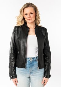 Zwarte leren jas met een slim fit ontwerp, ritssluiting aan de voorkant en zijzakken. Soepele textuur en minimalistische kraag. Gecombineerd met lichtblauwe high-waisted spijkerbroek.
