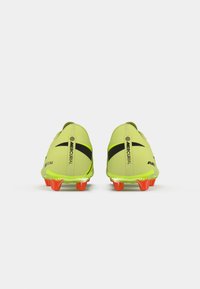 Botas de fútbol de color amarillo neón con un diseño elegante, detalles en negro y tachones de color naranja brillante. Construcción superior ligera para un rendimiento óptimo.
