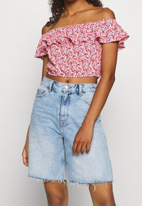 Rode bloemmotieven off-the-shoulder crop top met ruches, gecombineerd met lichtblauwe denimshorts met een rafelige zoom en hoge taille.