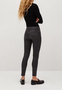 Jeans ajustados grises hechos de un material liso y elástico, con una cintura alta, bolsillos traseros y combinados con mocasines negros.