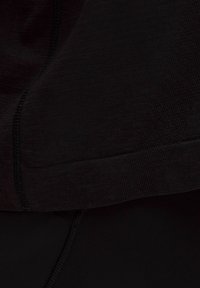 Close-up van zwart naadloos stof met gestikte naden en ribbelstructuurdetails.