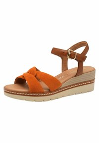 Sandalia de cuña de ante naranja con tiras cruzadas, acentos de cuero marrón claro, hebilla ajustable y suela de plataforma texturizada en crema.