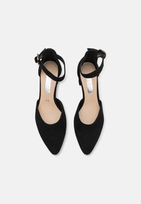 Black suede high-heeled shoes with a pointed toe design. Ankle strap with a silver buckle accent. Light beige insole with size label.