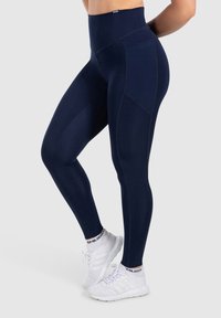 Leggings a vita alta blu navy con una consistenza liscia e elastica. Presentano tasche laterali e cuciture piatte per una maggiore comodità e durata.