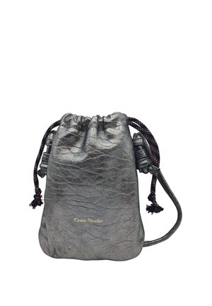 Petit sac en cuir gris métallique avec cordons noir et rouge, et « Craie Studio » imprimé en doré sur le devant.