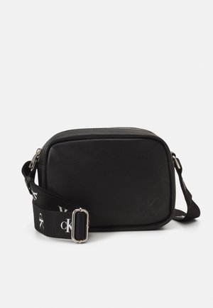 Musta nahkainen olkapussukka, jossa on suorakaiteen muotoinen rakenne, hopeanväriset pinnat ja säädettävä hihna, jossa on logokuvio.