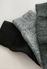Set of three socks in black, grey, and a mixed grey pattern. Features a soft, textured knit with ribbed cuffs for a snug fit.