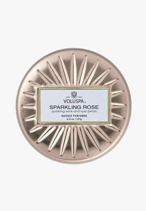 Pyöreä, metallinen kynttiläkippo, jossa on ruusukultainen viimeistely ja auringonsäteitä muistuttava koriste. Etiketissä lukee "Voluspa Sparkling Rose" mustalla ja valkoisella.