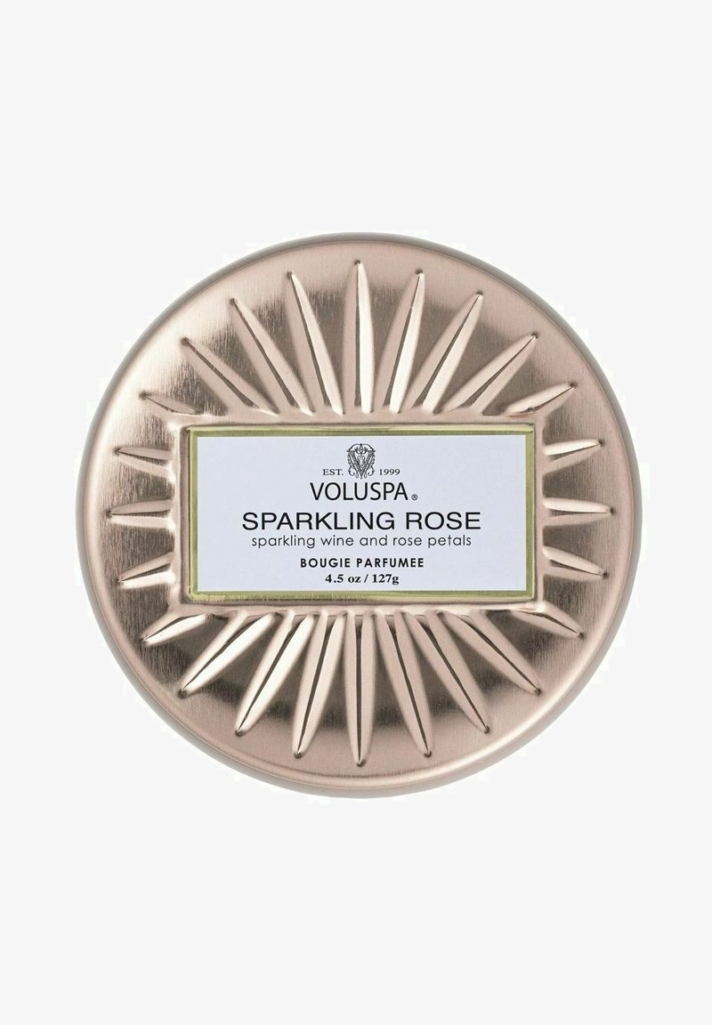 Pyöreä, metallinen kynttiläkippo, jossa on ruusukultainen viimeistely ja auringonsäteitä muistuttava koriste. Etiketissä lukee "Voluspa Sparkling Rose" mustalla ja valkoisella.