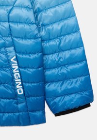 Blå puffjakke med gradient-effekt, med quiltet tekstur og en hvit "VINGINO" logo på siden, svart detalj ved mansjettene.