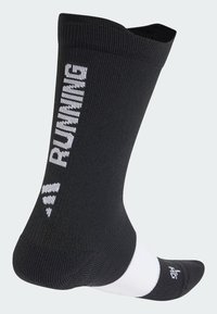 Chaussettes de course noires avec texture côtelée, arborant le texte blanc "RUNNING" sur le côté et une accentuation blanche au niveau de la cheville.