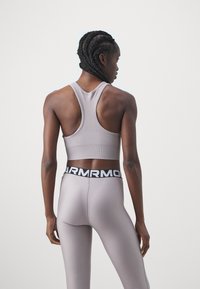 Sostegno grigio chiaro per attività sportive con design a schiena scoperta, abbinato a leggings attillati coordinati con una cintura nera con marchio.