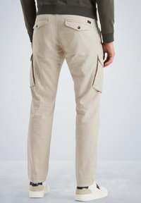 Pantalones cargo beige con dos bolsillos laterales y dos bolsillos traseros, fabricados con una tela suave. El diseño presenta un ajuste ceñido y una textura lisa.