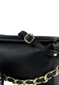 Sac à main en cuir noir avec une surface texturée, des ferrures dorées et un accent de chaîne épaisse. Il est doté d'une sangle plate avec une boucle ajustable.