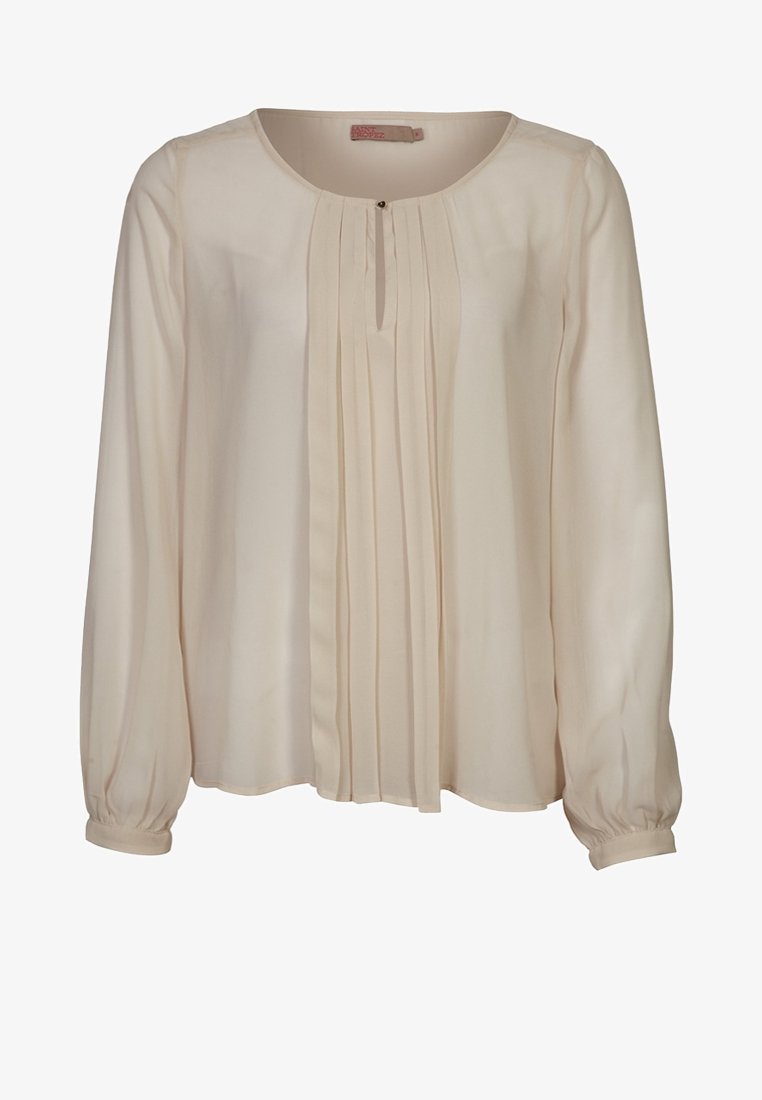 Blouse crème à manches longues avec encolure ronde, plis verticaux sur le devant et poignets boutonnés.